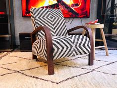 a chair sitting in front of a fire place with a painting on the wall behind it