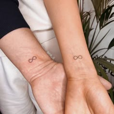 two people with matching tattoos on their wrists, both holding each other's hands