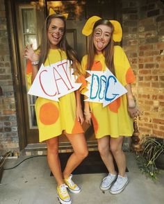 two girls in costumes holding up signs that say cat and dog