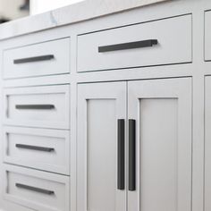 a white cabinet with black handles and knobs