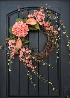 a wreath with pink flowers is hanging on the door to a black front door,