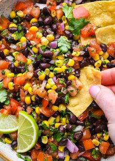 a bowl filled with black beans, corn and cilantro next to tortilla chips