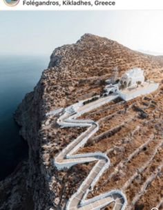 an aerial view of a winding road on the side of a cliff overlooking the ocean