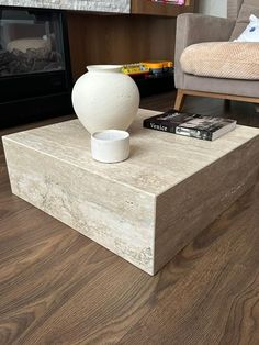 a white vase sitting on top of a wooden table next to a couch and fireplace