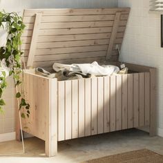 a wooden bench with shoes on it next to a potted plant in the corner