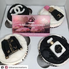 three cakes decorated with black and white icing are in a box, one has a chanel bag on it