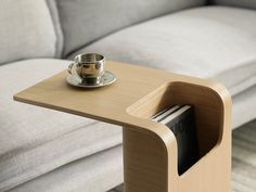 a wooden table with a cup and saucer on it next to a gray couch