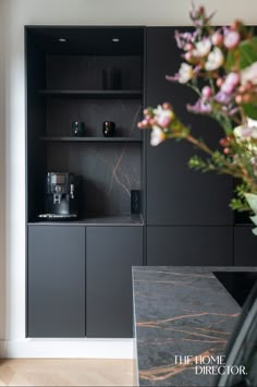 a vase with flowers sitting on top of a counter next to a shelf filled with bottles