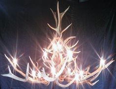 a chandelier made out of antlers is lit up in front of a black background