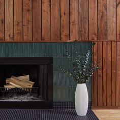 a fireplace with wood paneling and a white vase filled with flowers next to it