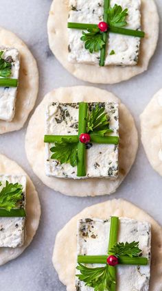 crackers with cheese and parsley on them sitting on top of a white surface