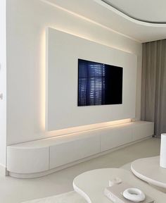 a living room with white furniture and a flat screen tv mounted on the wall above it