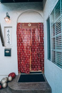 a red tiled door and some pumpkins on the steps