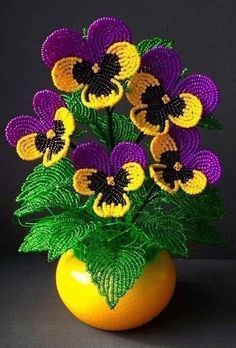 crocheted flowers in a yellow vase with green leaves