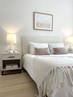 a white bed sitting in a bedroom next to two lamps on either side of it