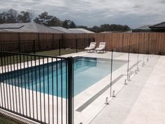 a fenced in swimming pool with chairs around it