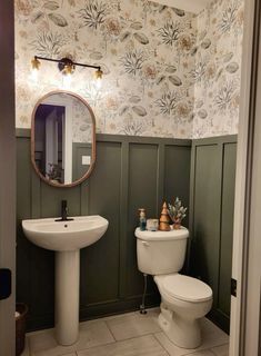 a white toilet sitting next to a sink in a bathroom under a large round mirror