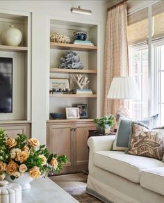 a living room filled with furniture and a flat screen tv mounted on a wall next to a window