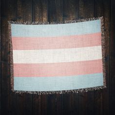 a pink and blue striped rug hanging on a wooden wall