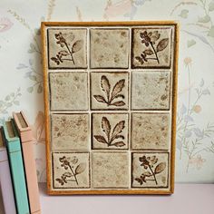 a ceramic tile with leaves on it next to some books and a bookender