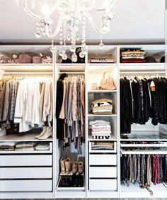 an organized closet with white drawers and chandelier hanging from it's ceiling