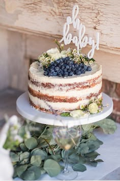 a cake sitting on top of a table next to greenery and a wooden sign