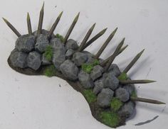 a rock and grass planter with spikes sticking out of it's sides on a white surface