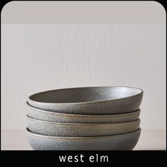 a stack of gray bowls sitting on top of a table