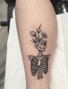 a black and white skeleton tattoo with flowers on it's back leg, showing the ribcage