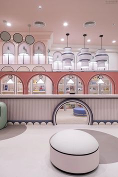 the interior of a store with circular windows and pink walls, white furniture and round mirrors