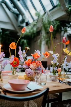 the table is set with flowers in vases, plates and utensils on it