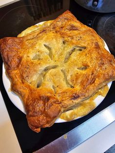 a pie sitting on top of a white plate next to an open stovetop oven