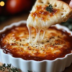 a piece of cheese pizza being lifted from a pie dish with tomato sauce and herbs