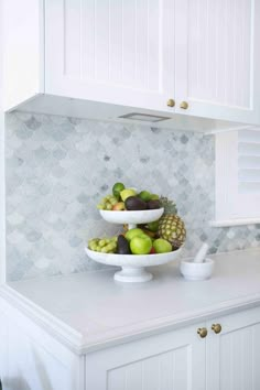 a bowl of fruit sitting on top of a white counter