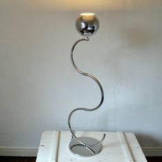 a metal lamp sitting on top of a white table next to a light fixture in a room