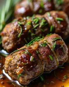 some meatballs are on a plate with sauce and garnished with green herbs