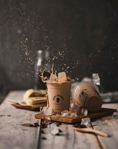 a cup of coffee is being sprinkled with sugar and cinnamon on a wooden table