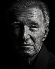 black and white photograph of an old man with wrinkles on his face, looking at the camera