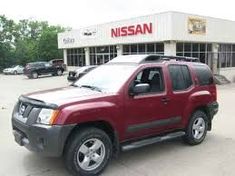 a red suv parked in front of a nissan dealership