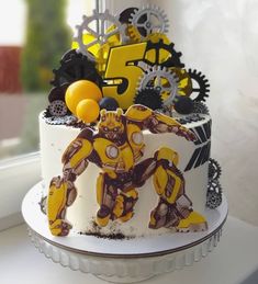 a yellow and black robot cake with gears on the top is ready to be eaten