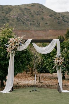 an outdoor ceremony setup with white drapes and flowers