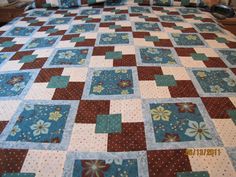 a bed with a blue and brown quilt on it