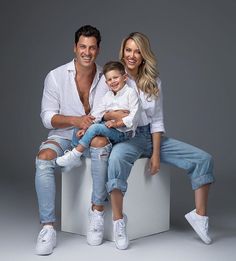 a man and woman sitting on top of a white box holding a small child in their lap