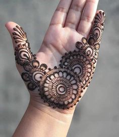 a woman's hand with henna tattoos on it, showing the intricate design