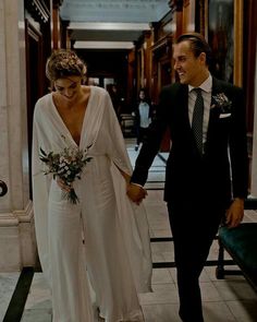 a bride and groom walking down the hall holding hands