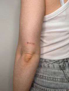 a woman's arm with the word music tattooed on her left arm, in black ink