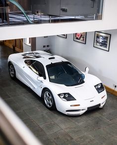 a white sports car is parked in a garage with pictures on the wall behind it