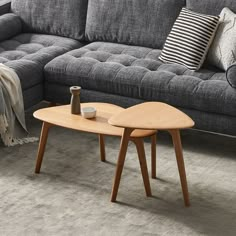 a living room with a gray couch and wooden coffee table on carpeted flooring