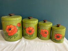 three green canisters with orange flowers painted on them