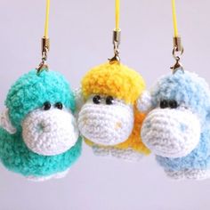 three crocheted monkey key chains hanging from yellow hooks, one blue and one green